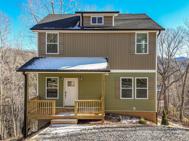 back of property featuring covered porch and a shingled roof