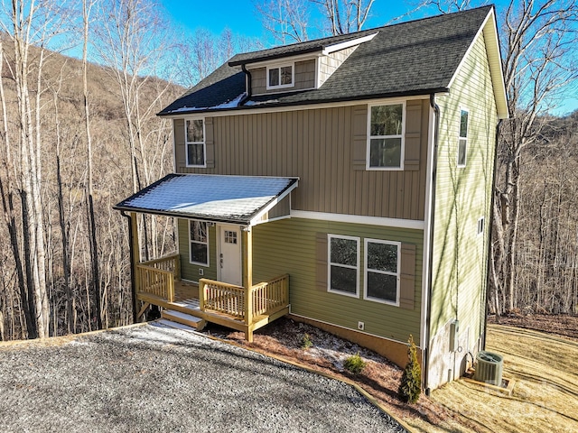 view of front of house with a shingled roof and central AC