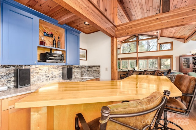 bar with blue cabinets, vaulted ceiling with beams, wooden ceiling, and decorative backsplash