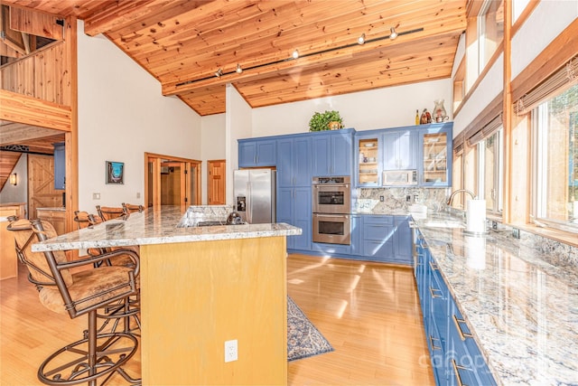 kitchen with a kitchen bar, blue cabinetry, wooden ceiling, and appliances with stainless steel finishes