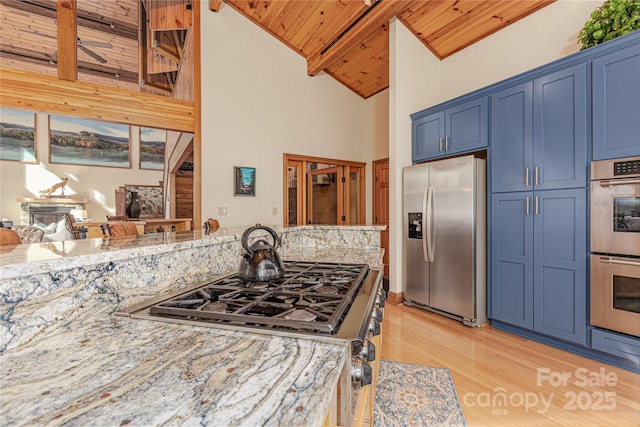 kitchen with light stone counters, appliances with stainless steel finishes, blue cabinets, and wooden ceiling