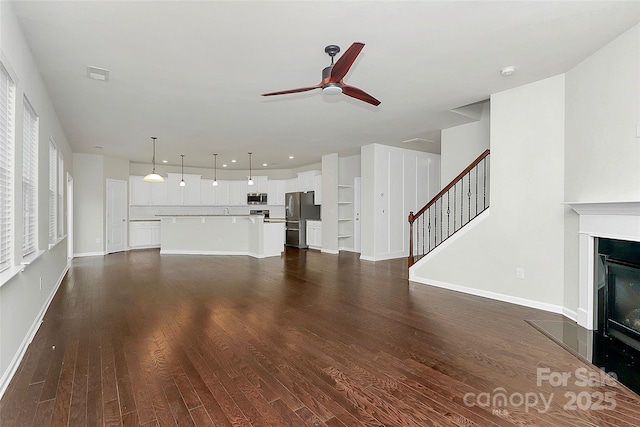 unfurnished living room featuring dark hardwood / wood-style floors and ceiling fan