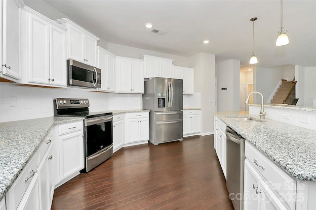 kitchen with white cabinetry, appliances with stainless steel finishes, sink, and light stone counters