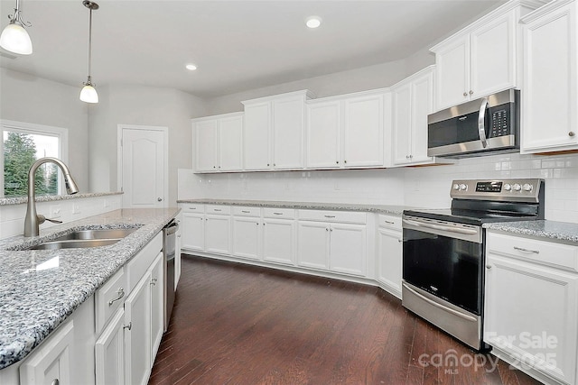 kitchen featuring appliances with stainless steel finishes, sink, white cabinets, and decorative light fixtures