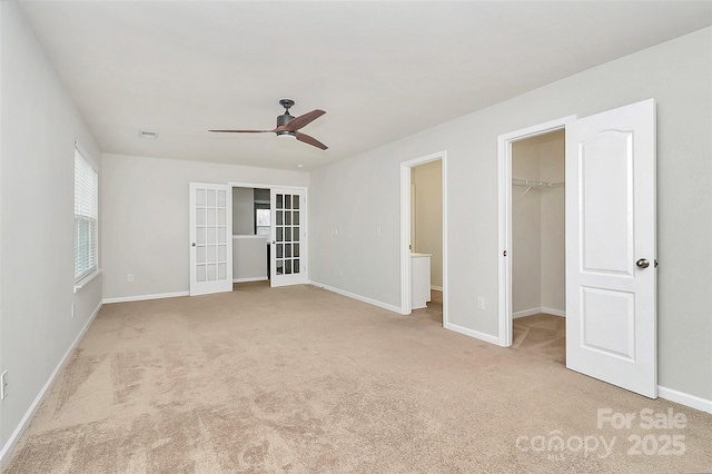 unfurnished bedroom with french doors, a walk in closet, light carpet, a closet, and ceiling fan