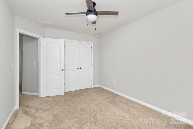 unfurnished bedroom with light carpet, a closet, and ceiling fan