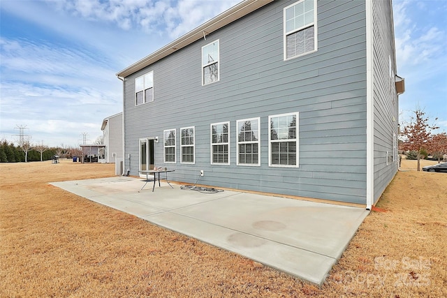 back of house with a patio and a lawn