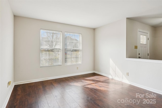 spare room featuring a healthy amount of sunlight and dark hardwood / wood-style floors