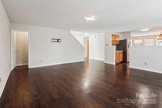 unfurnished living room with an inviting chandelier and dark hardwood / wood-style flooring