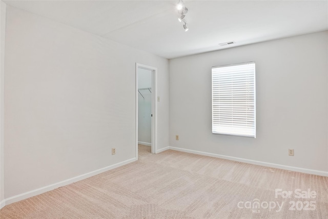 carpeted empty room featuring rail lighting