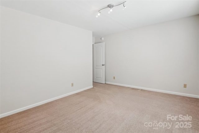 carpeted empty room featuring track lighting