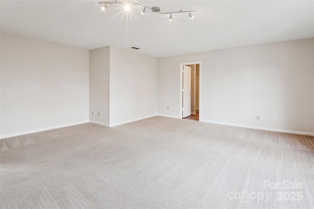 carpeted empty room featuring rail lighting