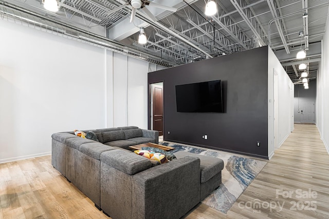 living room featuring ceiling fan, a towering ceiling, and hardwood / wood-style floors