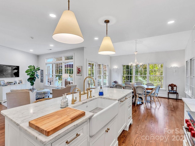 kitchen featuring white cabinetry, plenty of natural light, a center island with sink, and decorative light fixtures