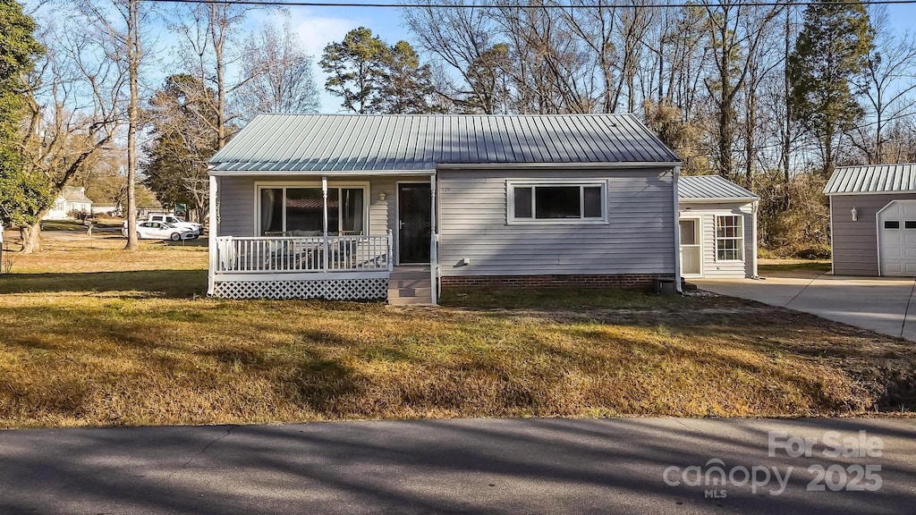 view of front of property featuring an outbuilding, a porch, a garage, and a front yard