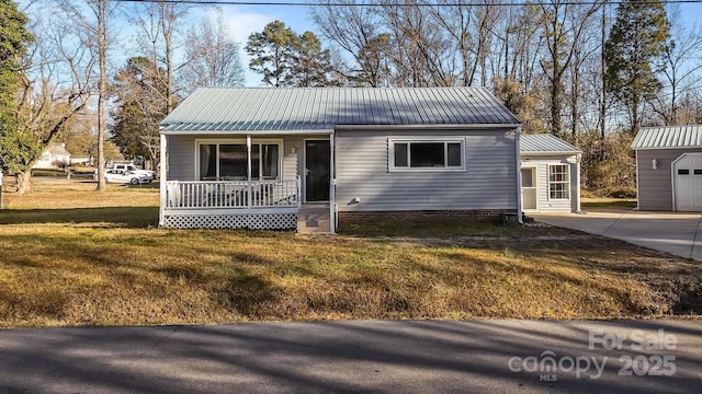 view of front of property featuring an outbuilding, a porch, a garage, and a front yard