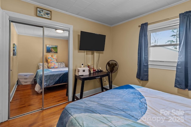 bedroom with hardwood / wood-style flooring, ornamental molding, and a closet