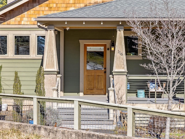 doorway to property with roof with shingles