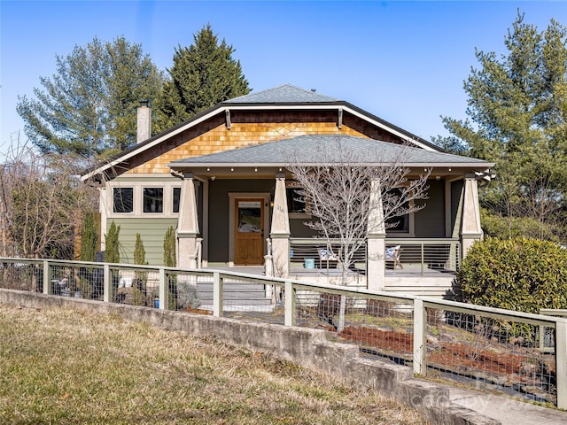 view of front of home with roof with shingles, fence, and a chimney