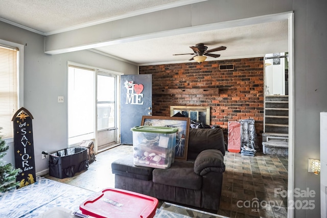 living room featuring ceiling fan, crown molding, a textured ceiling, and brick wall