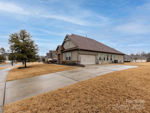 view of side of home with a garage, central AC, and a lawn