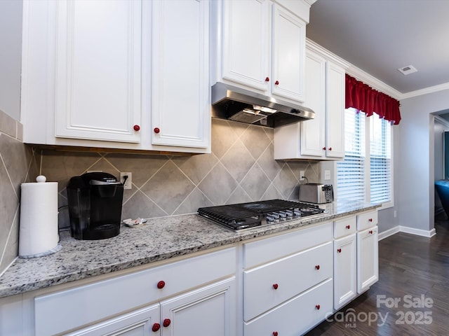 kitchen with light stone counters, ornamental molding, and white cabinets