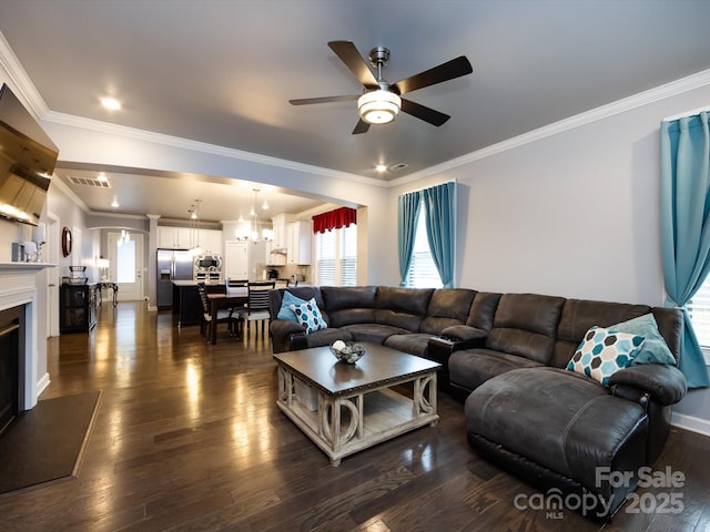 living room with dark hardwood / wood-style flooring, ceiling fan with notable chandelier, and ornamental molding