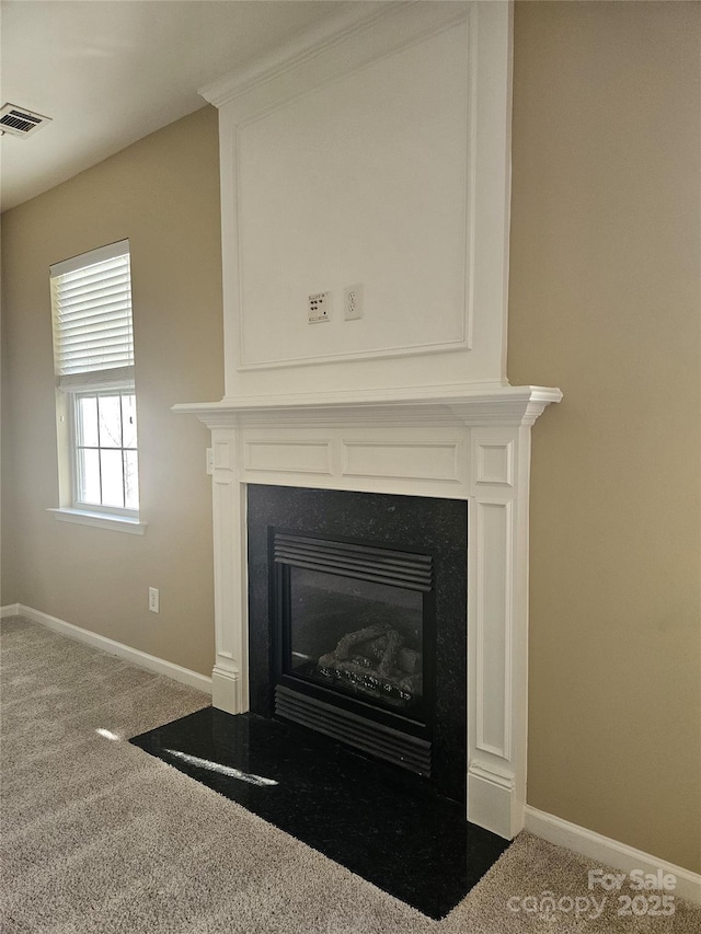 details featuring visible vents, a fireplace with flush hearth, baseboards, and carpet flooring