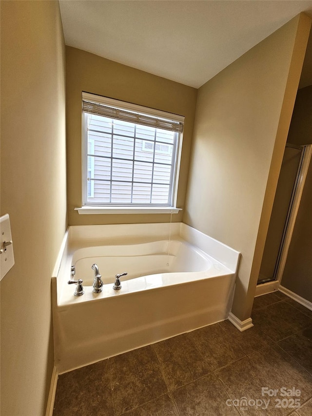 full bathroom featuring baseboards, a bath, and a shower stall