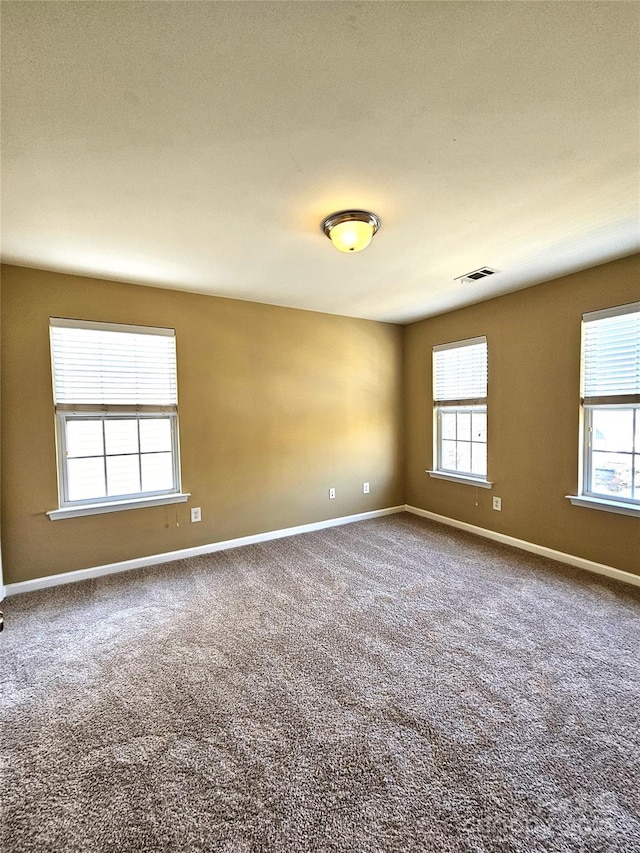 empty room featuring visible vents, baseboards, and carpet flooring