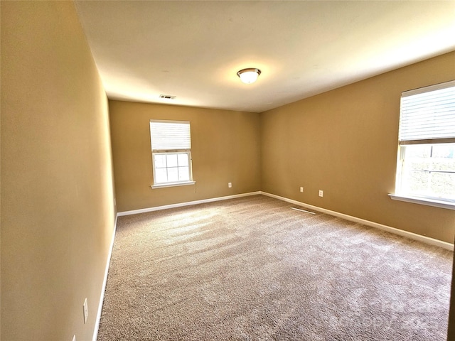 carpeted empty room with visible vents and baseboards