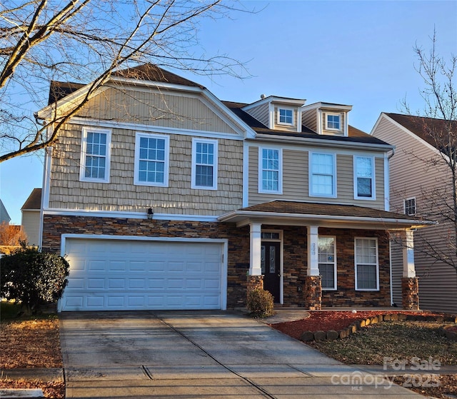 view of front of house featuring a garage, stone siding, and driveway