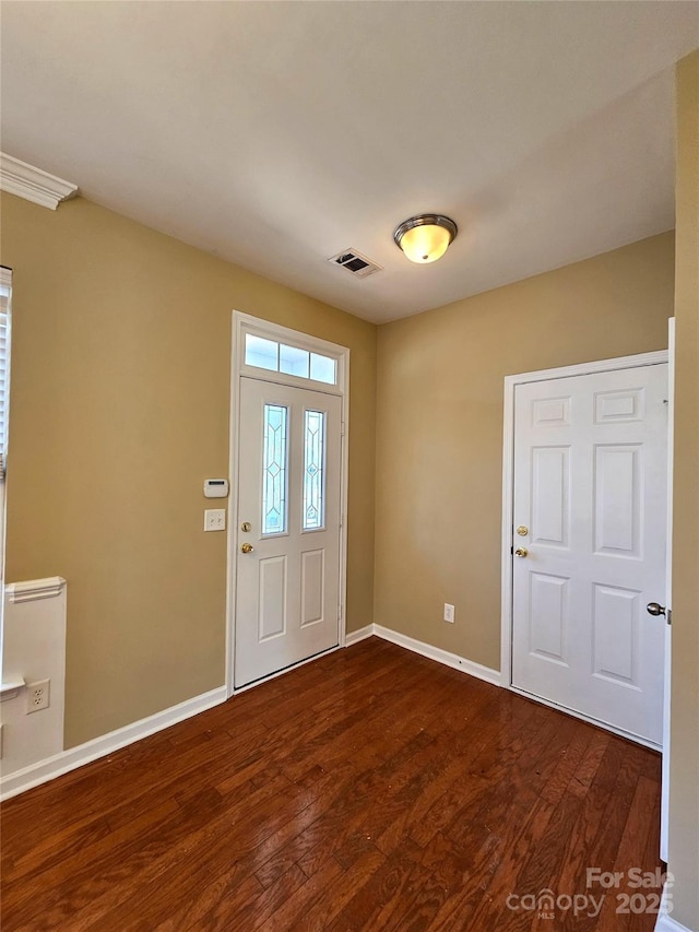 foyer entrance featuring visible vents, baseboards, and dark wood-style flooring