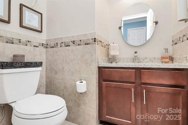 bathroom featuring vanity, toilet, and tile walls