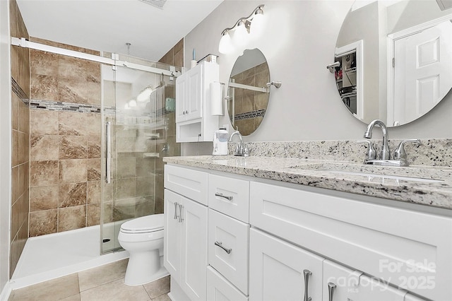 bathroom featuring vanity, toilet, tile patterned floors, and a shower with shower door