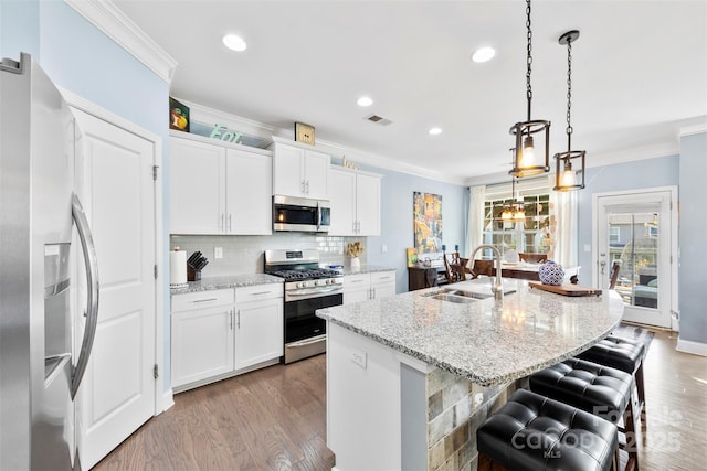 kitchen with stainless steel appliances, sink, a center island with sink, and white cabinets