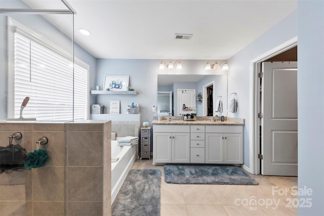 bathroom featuring vanity, tile patterned flooring, and a tub