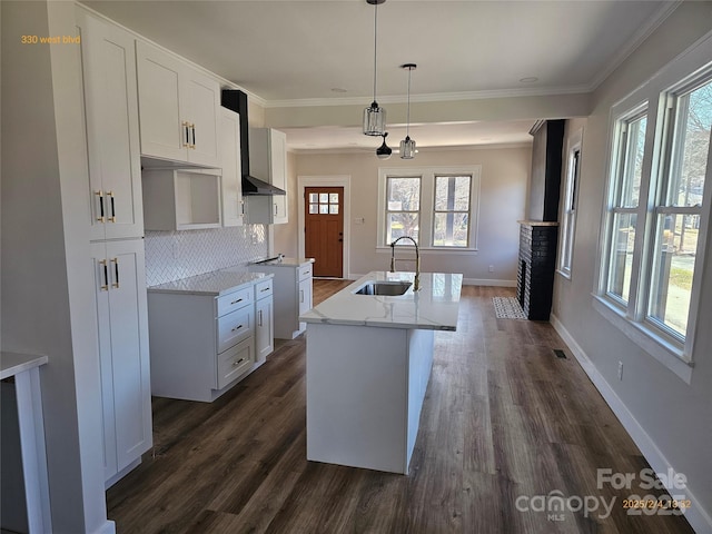 kitchen with dark hardwood / wood-style floors, decorative light fixtures, white cabinetry, sink, and a kitchen island with sink