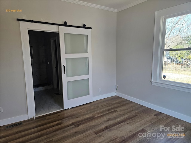 spare room featuring dark hardwood / wood-style flooring, crown molding, and a barn door