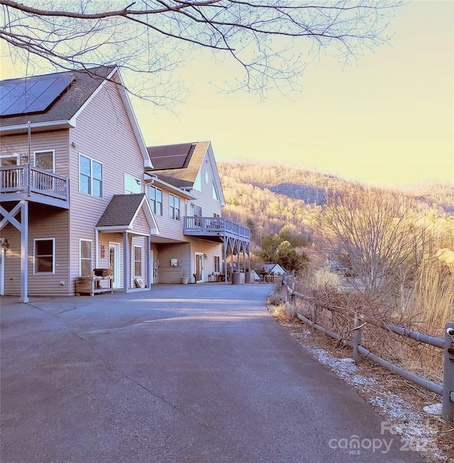 property exterior at dusk featuring a balcony and solar panels