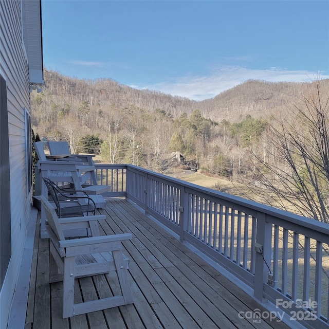 wooden deck with a wooded view and a mountain view