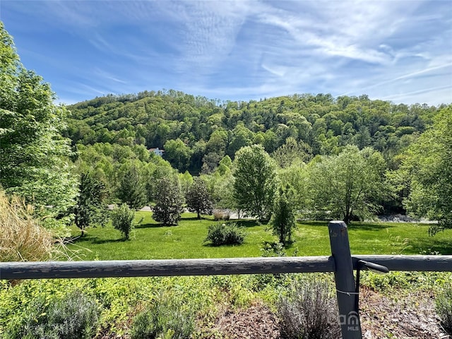 exterior space with a lawn, a view of trees, and fence