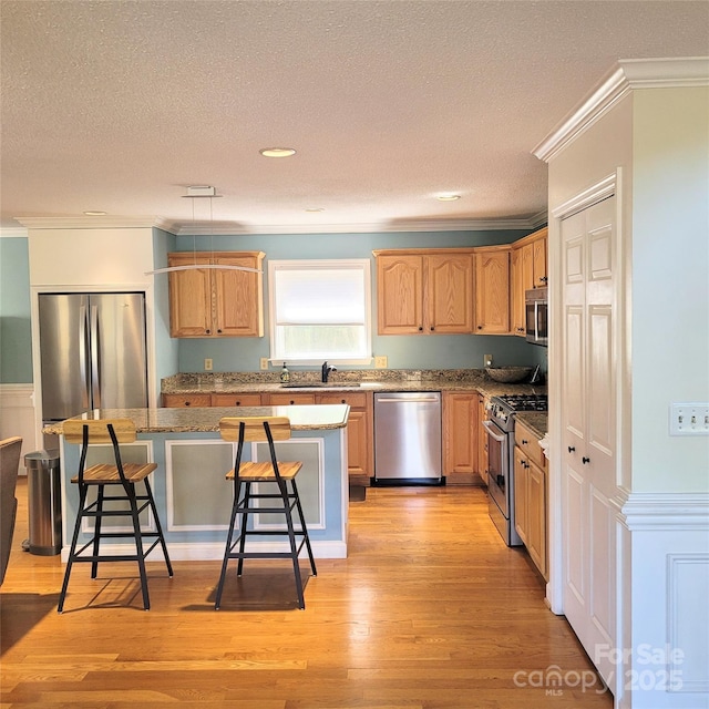 kitchen with ornamental molding, a kitchen island, stainless steel appliances, and a kitchen breakfast bar