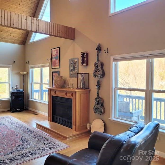 living room with light wood-style flooring, a glass covered fireplace, wood ceiling, and high vaulted ceiling