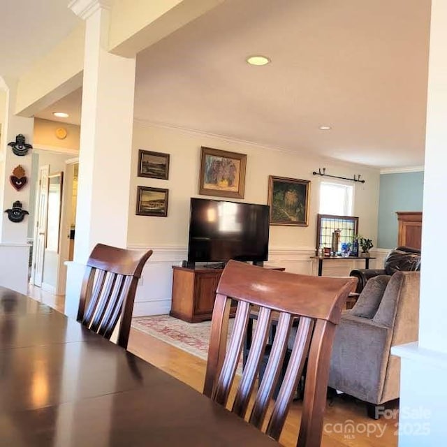 living room featuring a decorative wall, recessed lighting, ornamental molding, and a wainscoted wall