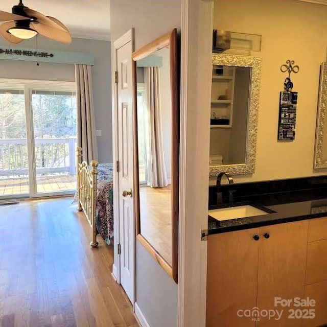 bathroom featuring crown molding, ceiling fan, vanity, wood finished floors, and visible vents