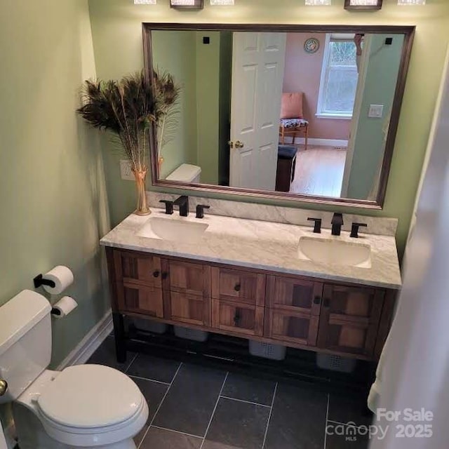 bathroom featuring toilet, baseboards, and a sink
