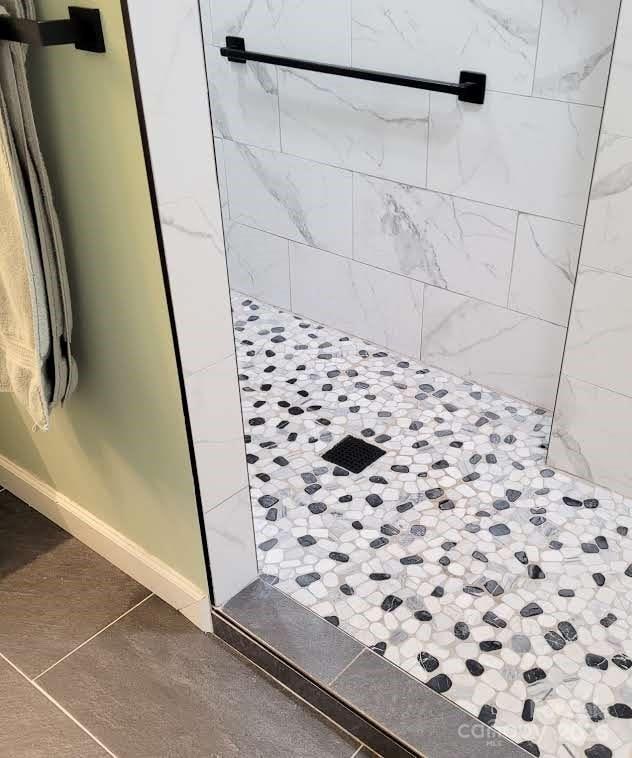 full bath featuring baseboards and tiled shower
