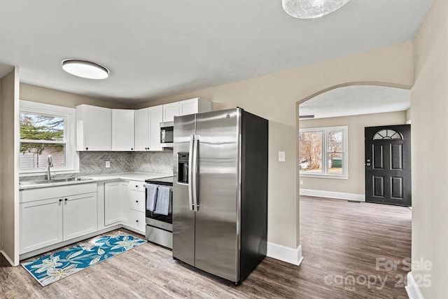 kitchen featuring stainless steel appliances, light hardwood / wood-style floors, sink, and white cabinets