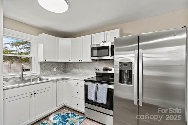 kitchen featuring white cabinetry, sink, backsplash, and stainless steel appliances